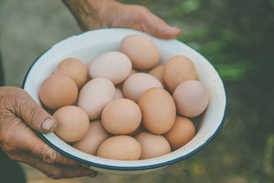 Cropped hands of senior woman holding eggs in bowl