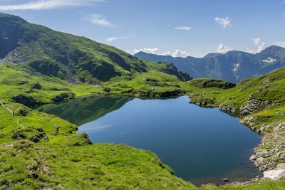 Scenic view of river by mountains against sky