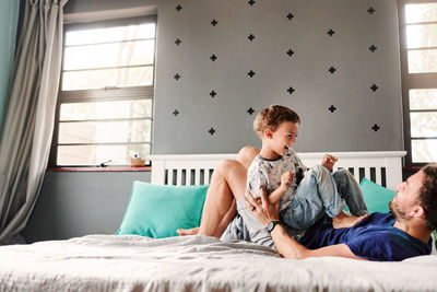 Father and son lying on bed at home