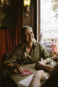 Smiling woman holding hand of man while having wine during date at restaurant