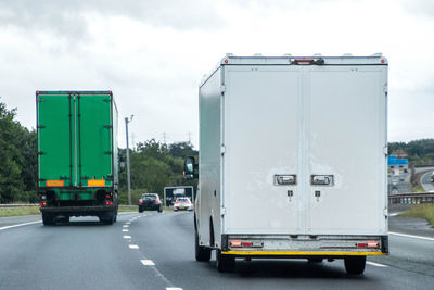 Vehicles on road against sky in city