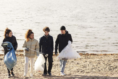 Male and female environmentalists with microplastics garbage walking against lake