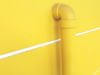 Close-up of yellow pipe against wall