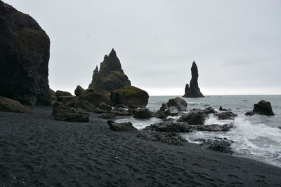 Rock formations on beach against sky