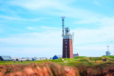 Tower on field by building against sky