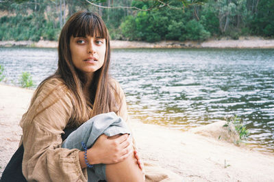 Portrait of young woman sitting by lake