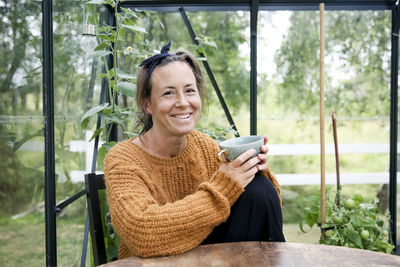 Woman having coffee in greenhouse