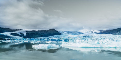 Scenic view of ice glacier against cloudy sky