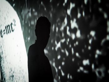 Silhouette woman standing against wall at night