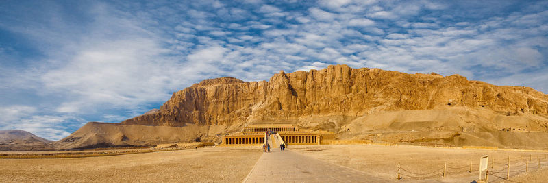 Rear view of man on rock formations in desert against sky