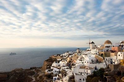 Town by sea against cloudy sky