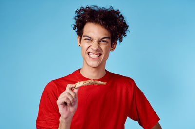 Portrait of smiling man holding ice cream against blue background