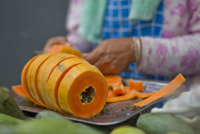 Midsection of woman cutting papaya on tray