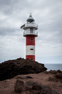 Lighthouse by sea against sky