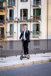 Full length of businessman riding electric scooter