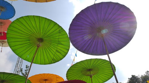 Low angle view of multi colored umbrellas hanging against sky