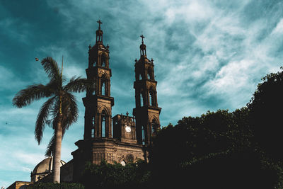 Low angle view of palm trees and building against sky