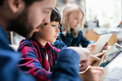 Close-up of teacher explaining students to use digital tablet at desk