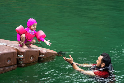 Portrait of smiling woman holding pink umbrella on boat