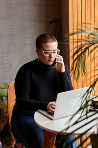 Young man using laptop while sitting on table