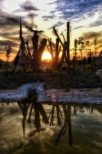 Scenic view of landscape against cloudy sky at sunset