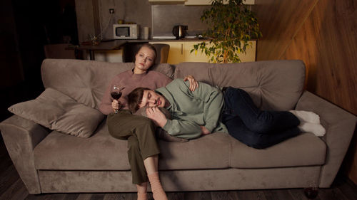 Woman holding wineglass sitting on sofa at home