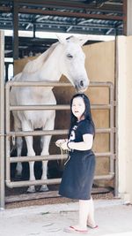 Portrait of girl standing by horse in stable