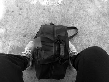 Low section of man with bag sitting outdoors