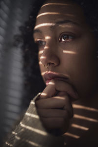 Pensive young woman looking through window