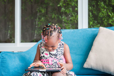 Girl looking away while sitting on sofa