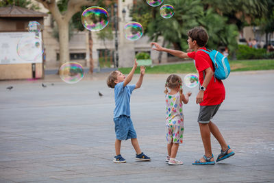 Rear view of siblings playing with bubbles at beach