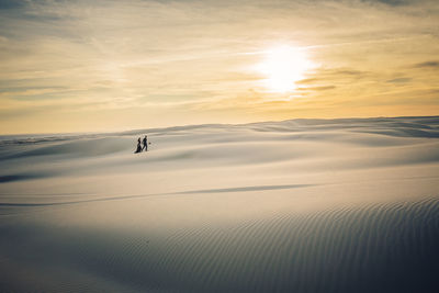 Person on land against sky during sunset