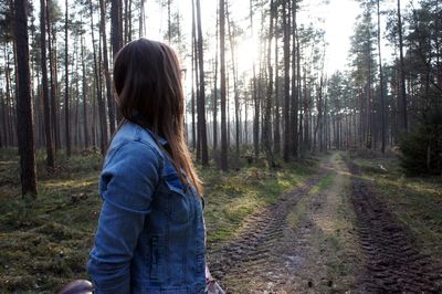 Woman standing against trees at forest