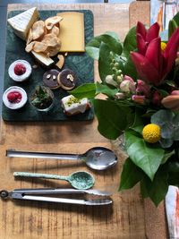 High angle view of food and flowers with kitchen utensils on table