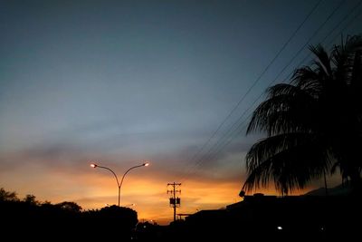 Silhouette trees against dramatic sky during sunset