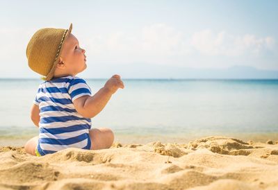 One children sit in the beach and laugh. 