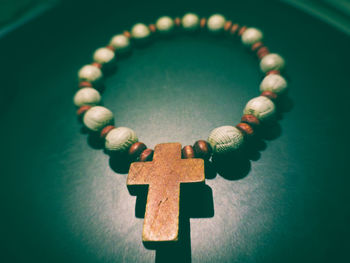 Close-up of wooden cross on bracelet over table