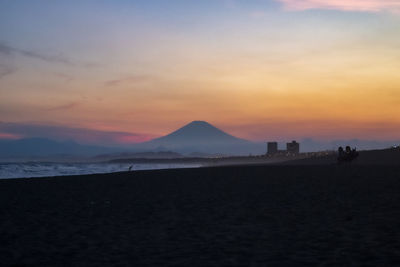 Scenic view of beach and fuji san against sky during sunset
