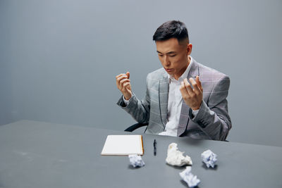 Side view of young man using mobile phone while standing against white background