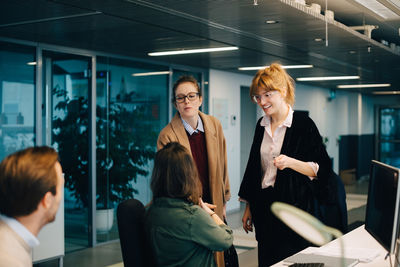 Businessman looking at smiling female colleagues greeting at creative office