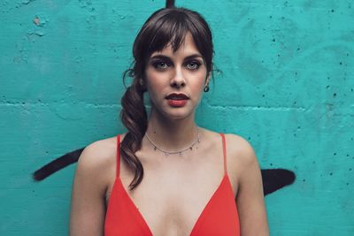 Portrait of young woman standing against wall