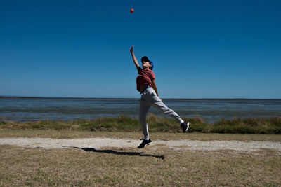 Full length of boy catching ball against beach