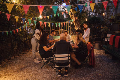 Multi-ethnic friends having dinner during garden party in backyard