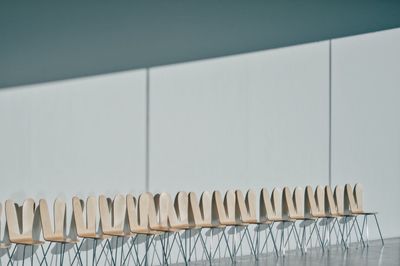 Empty chairs in row against wall