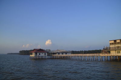 Houses by sea against clear blue sky