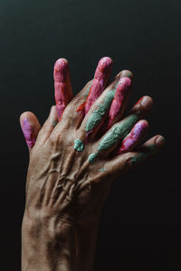 Cropped hands of woman with paint against black background