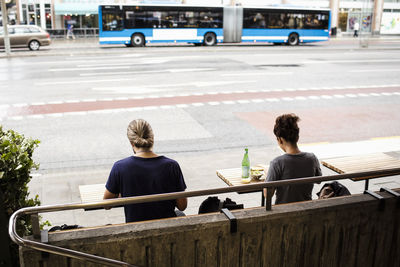 Rear view of man and woman sitting at sidewalk cafe in city