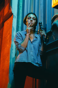 Portrait of young woman standing against wall