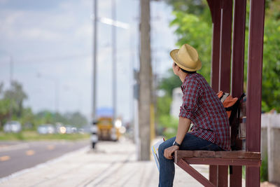 Side view of man using mobile phone while sitting outdoors