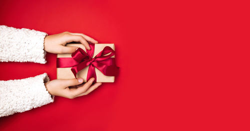 Cropped hand of woman holding gift against yellow background